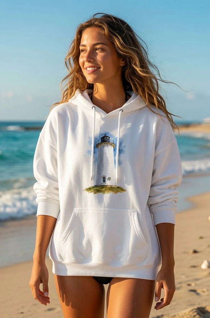 Woman wearing a white hoodie with a lighthouse design on a beach